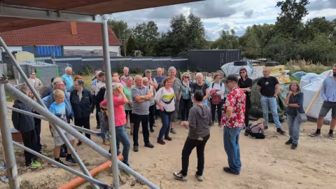 Die Bauherrschaft stellt einer Besuchergruppe das Earthship vor